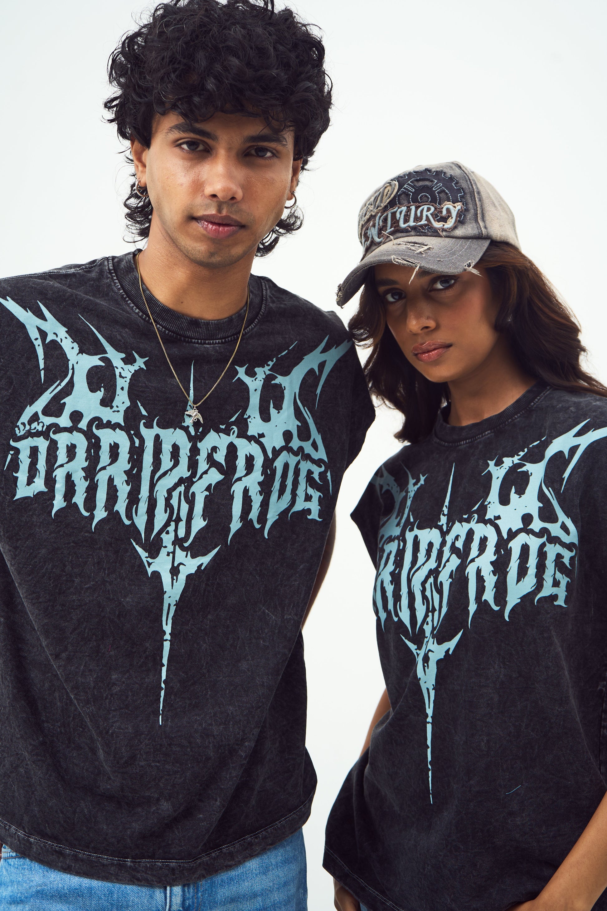 Two models wearing Stylera unisex gothic print sleeveless top in washed black with blue logo