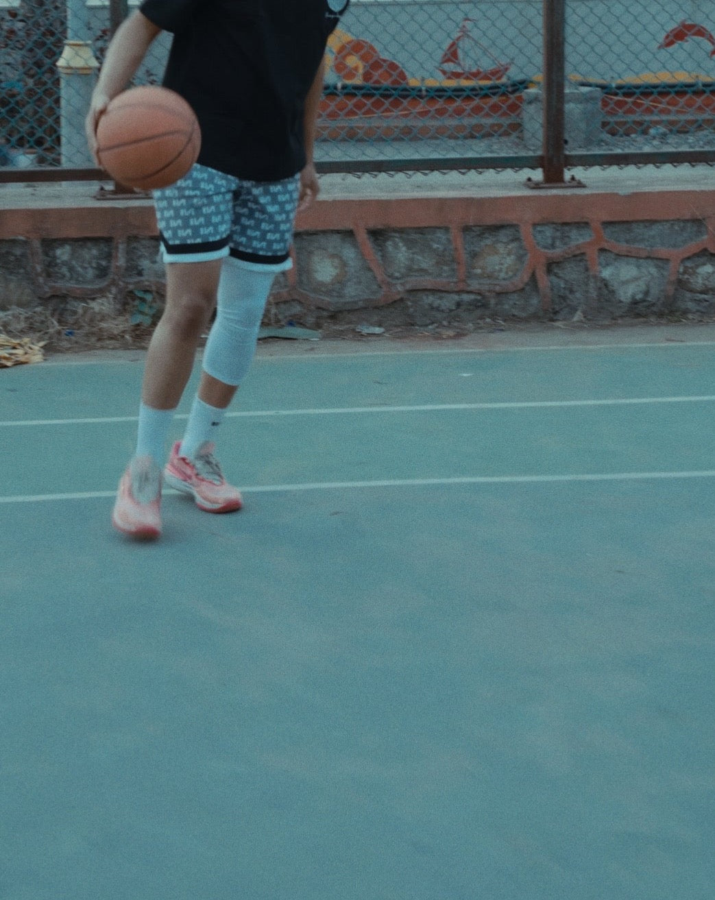 Stylera patterned athletic shorts worn by man dribbling a basketball on outdoor court trendy gym shorts for men