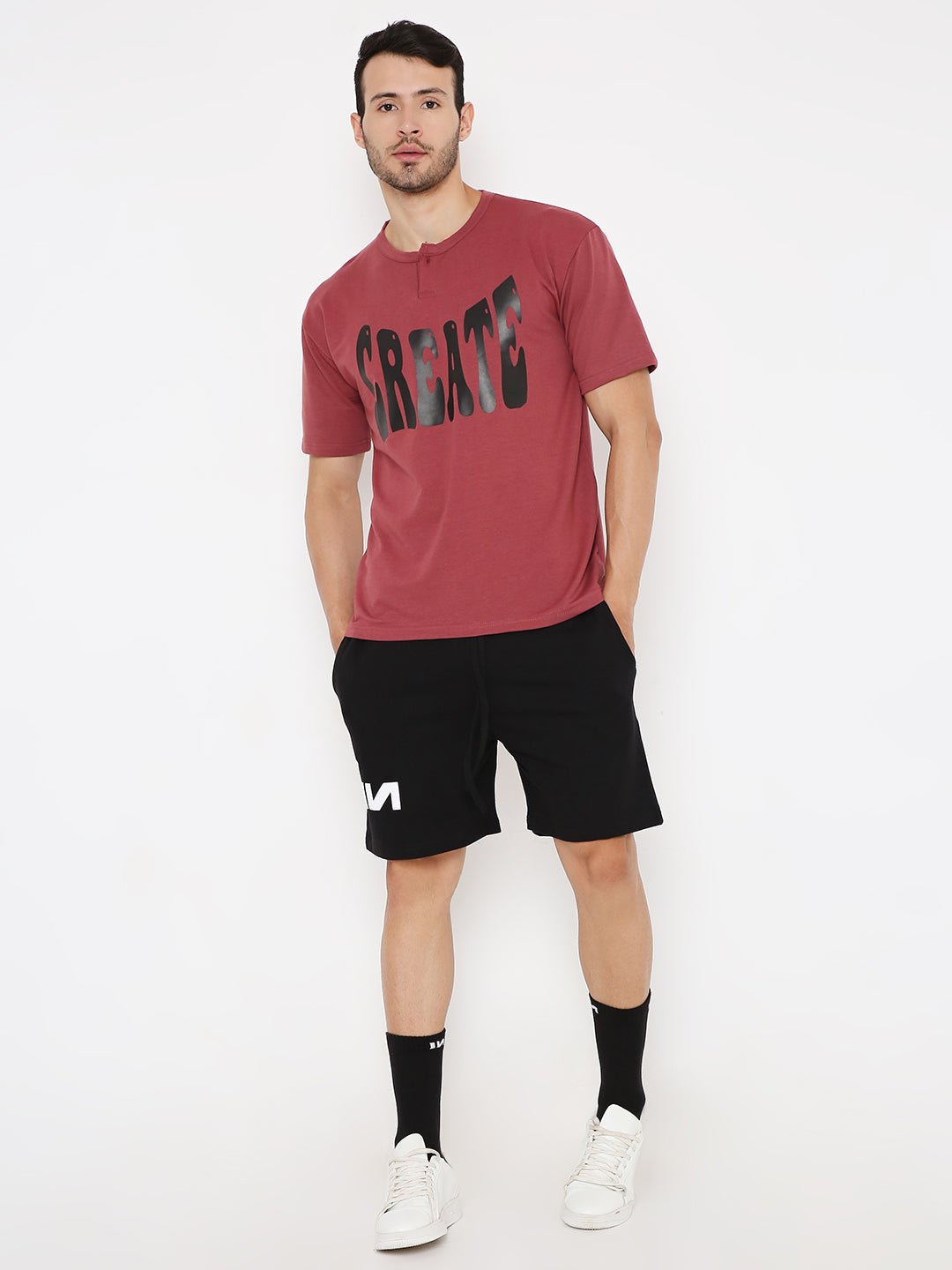 Male model wearing Stylera oversized onion red t-shirt paired with black shorts and white sneakers