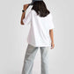 Woman wearing a white good vibes only graphic tee for women with light wash jeans and a blue cap