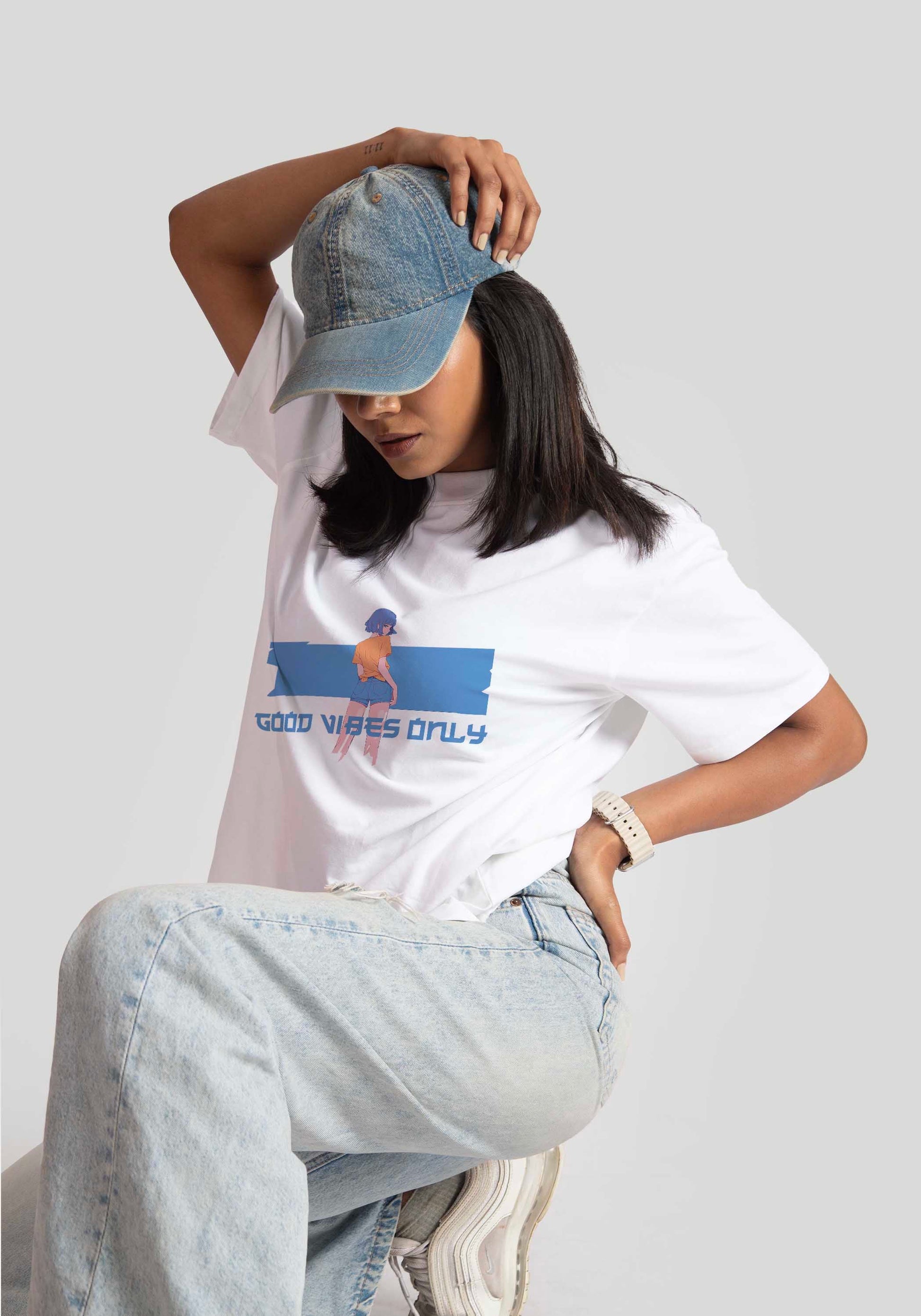Stylera good vibes only graphic tee for women worn with denim jeans and a blue cap