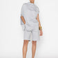 Stylera light gray statement top with draped design worn with matching shorts and black heels