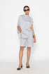 Stylera light gray statement top with draped design worn with matching shorts and black heels