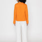 Back view of orange v-neck blouse for women paired with white wide-leg pants by Stylera