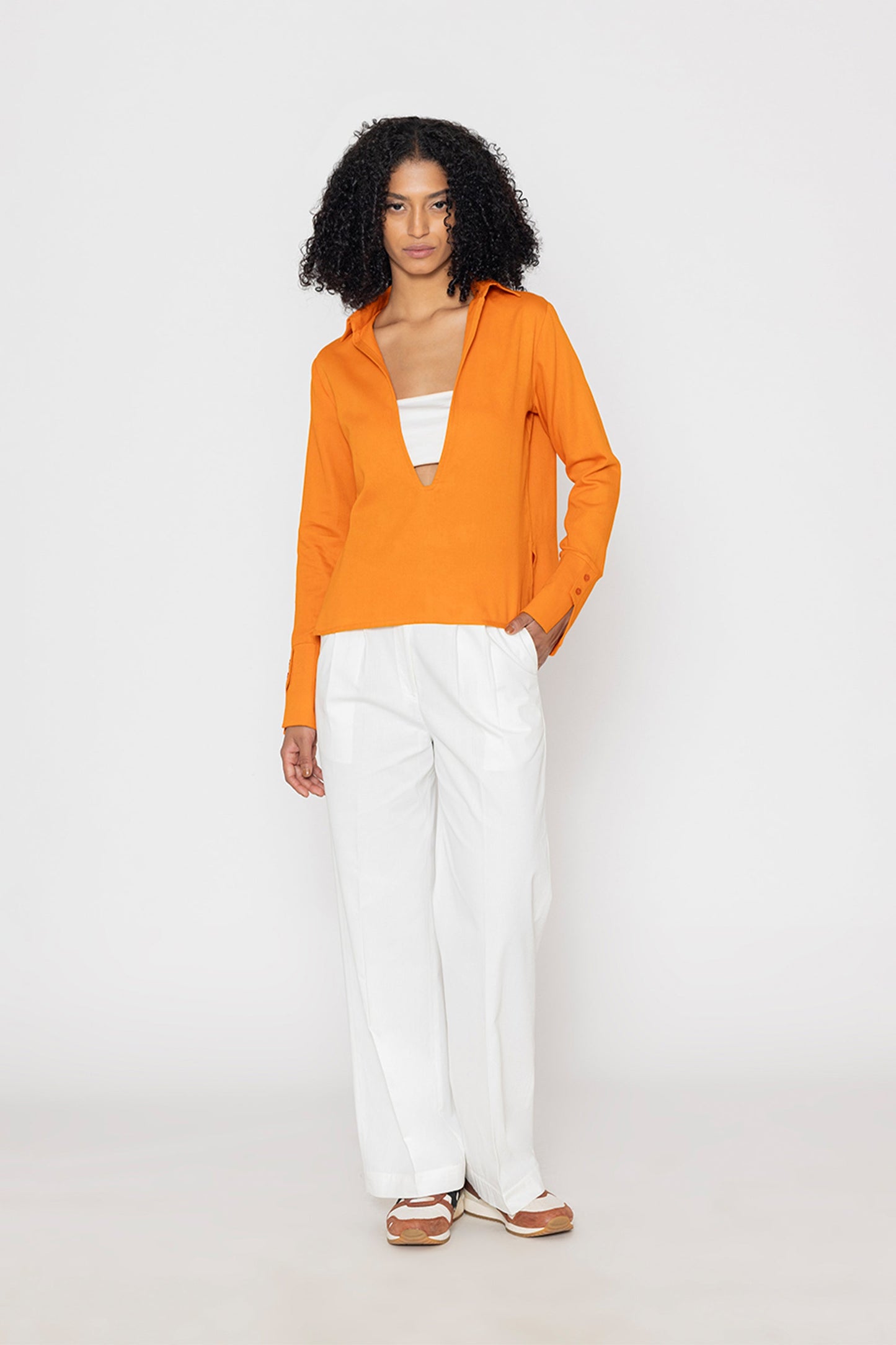 Stylera orange v-neck blouse for women paired with white pants on model