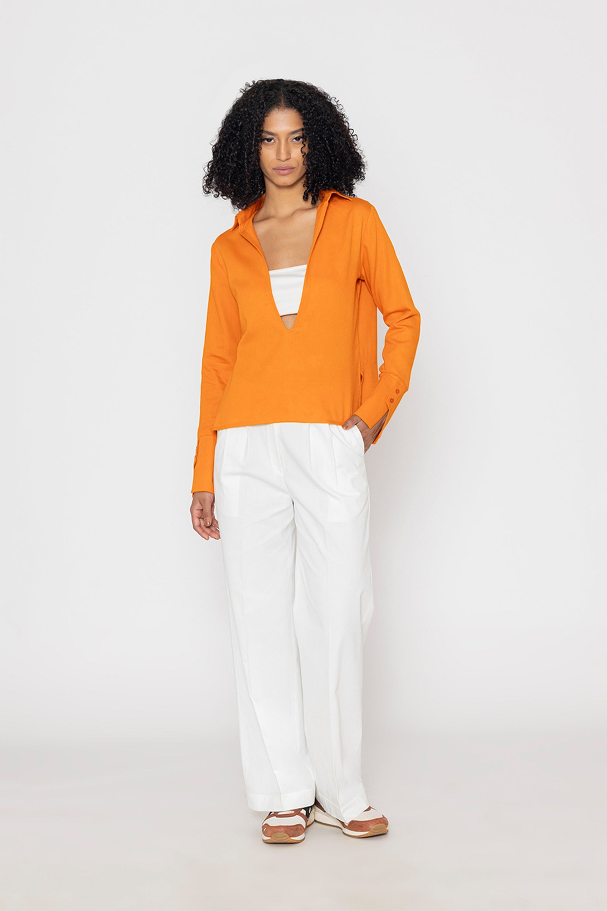Stylera orange v-neck blouse for women paired with white pants on model