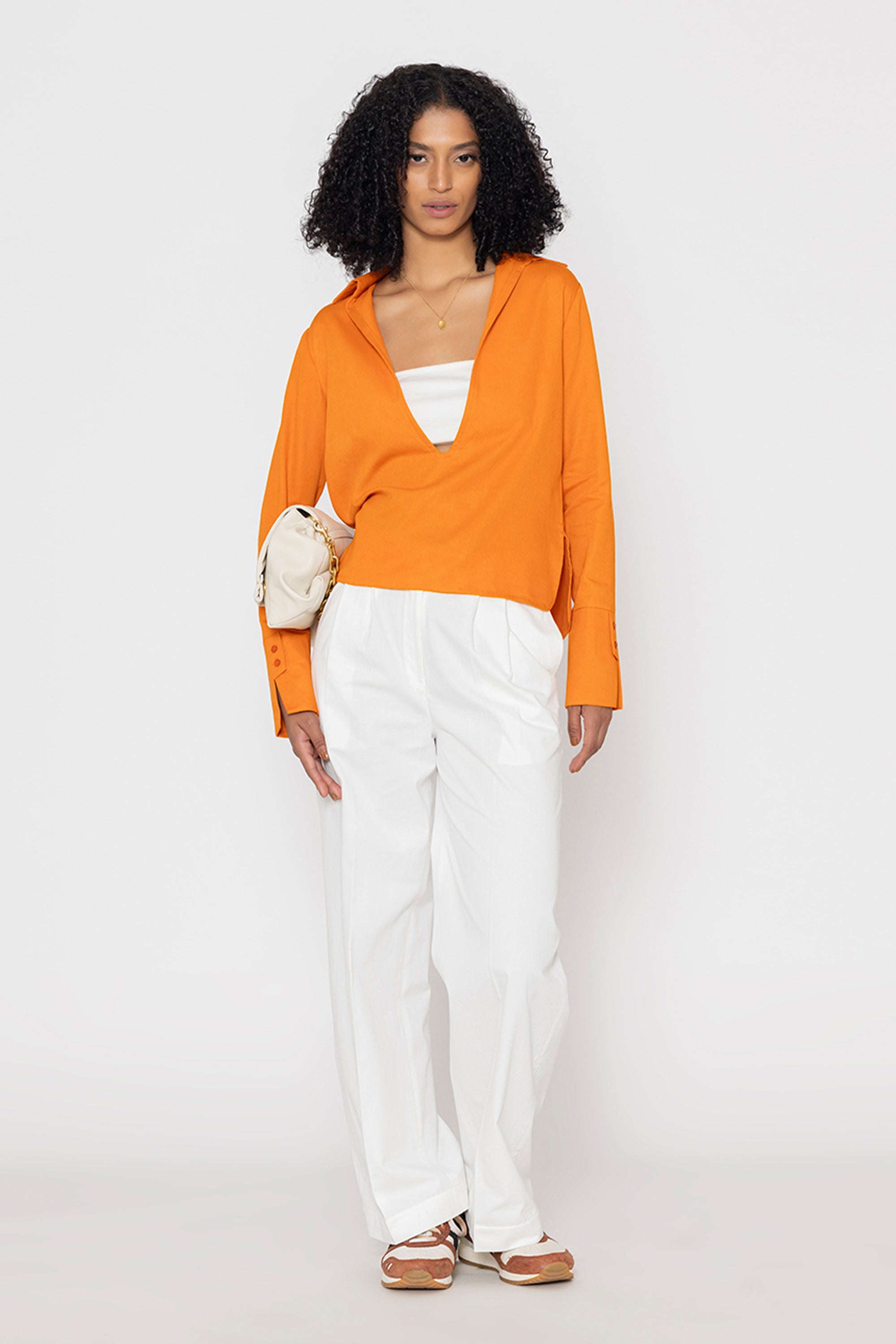 Stylera orange v-neck blouse for women styled with white pants and neutral accessories