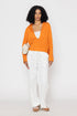 Stylera orange v-neck blouse for women styled with white pants and neutral accessories