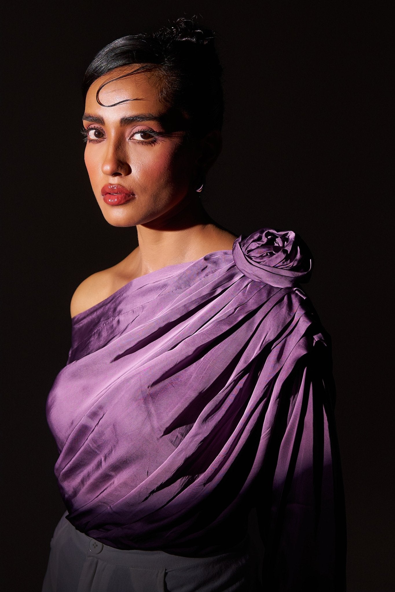 Stylera purple draped evening top with floral detail on shoulder styled on model