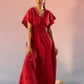 Stylera red Schiffli maxi dress with short sleeves and scalloped hem worn by model on rocks
