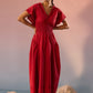 Stylera red Schiffli maxi dress with V-neck and flutter sleeves on model standing on rocks