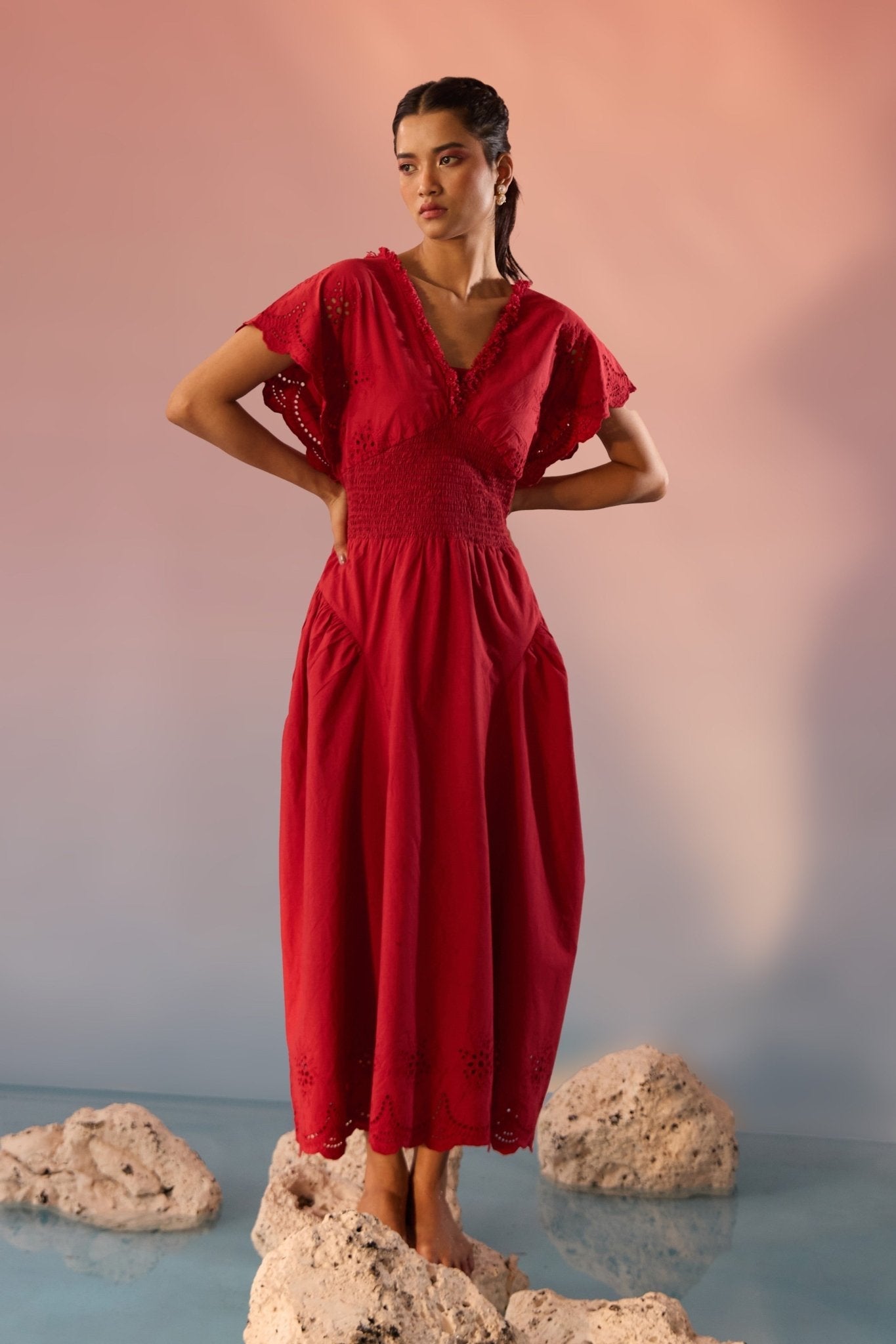 Stylera red Schiffli maxi dress with V-neck and flutter sleeves on model standing on rocks