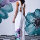 Model wearing white coral floral jumpsuit by Stylera with lace up back and watercolor floral print on leg