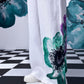 Stylera dungaree showing wide leg white coral floral jumpsuit with teal and purple floral print and white sneakers