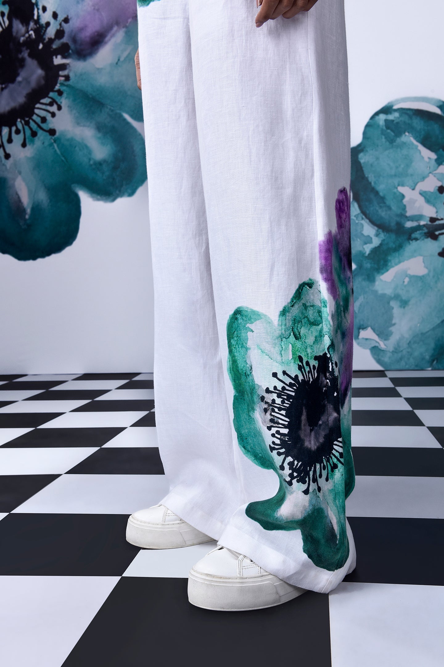 Stylera dungaree showing wide leg white coral floral jumpsuit with teal and purple floral print and white sneakers