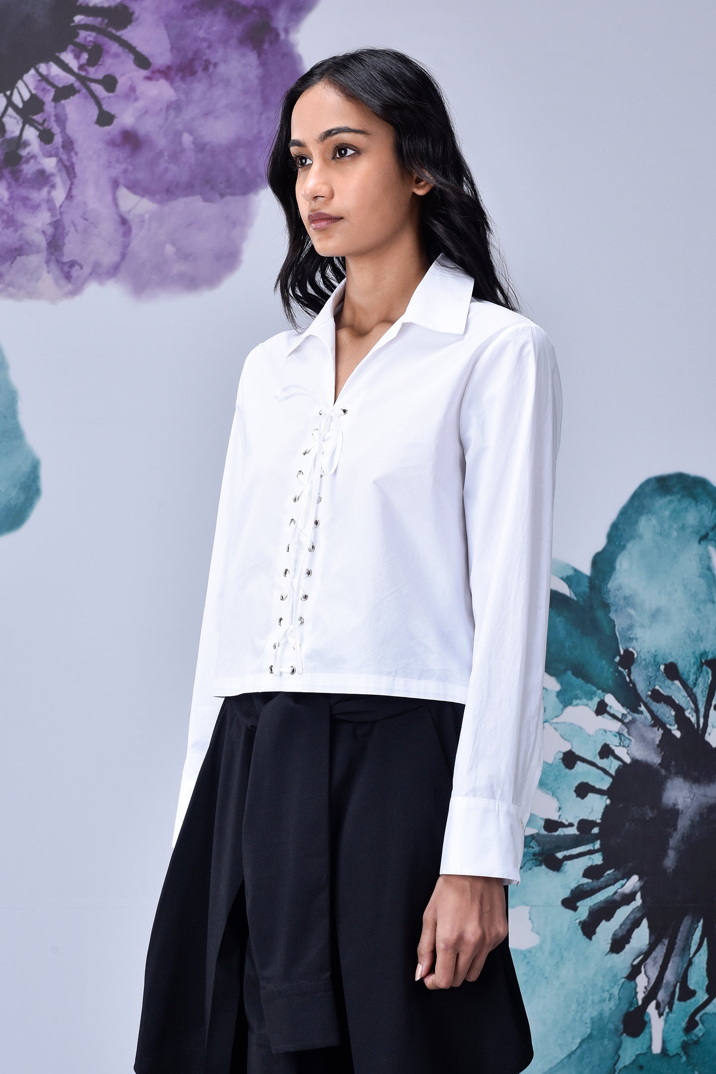Model wearing Stylera white cotton lace up shirt with collared neckline long sleeves over black skirt