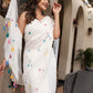 Elegant white cotton saree with tassels and colorful floral accents for festive occasions
