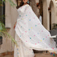 Elegant white cotton saree with tassels, featuring colorful floral motifs, perfect for festive occasions