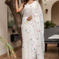 Elegant white cotton saree with tassels, featuring multicolored floral embroidery for a vibrant look.