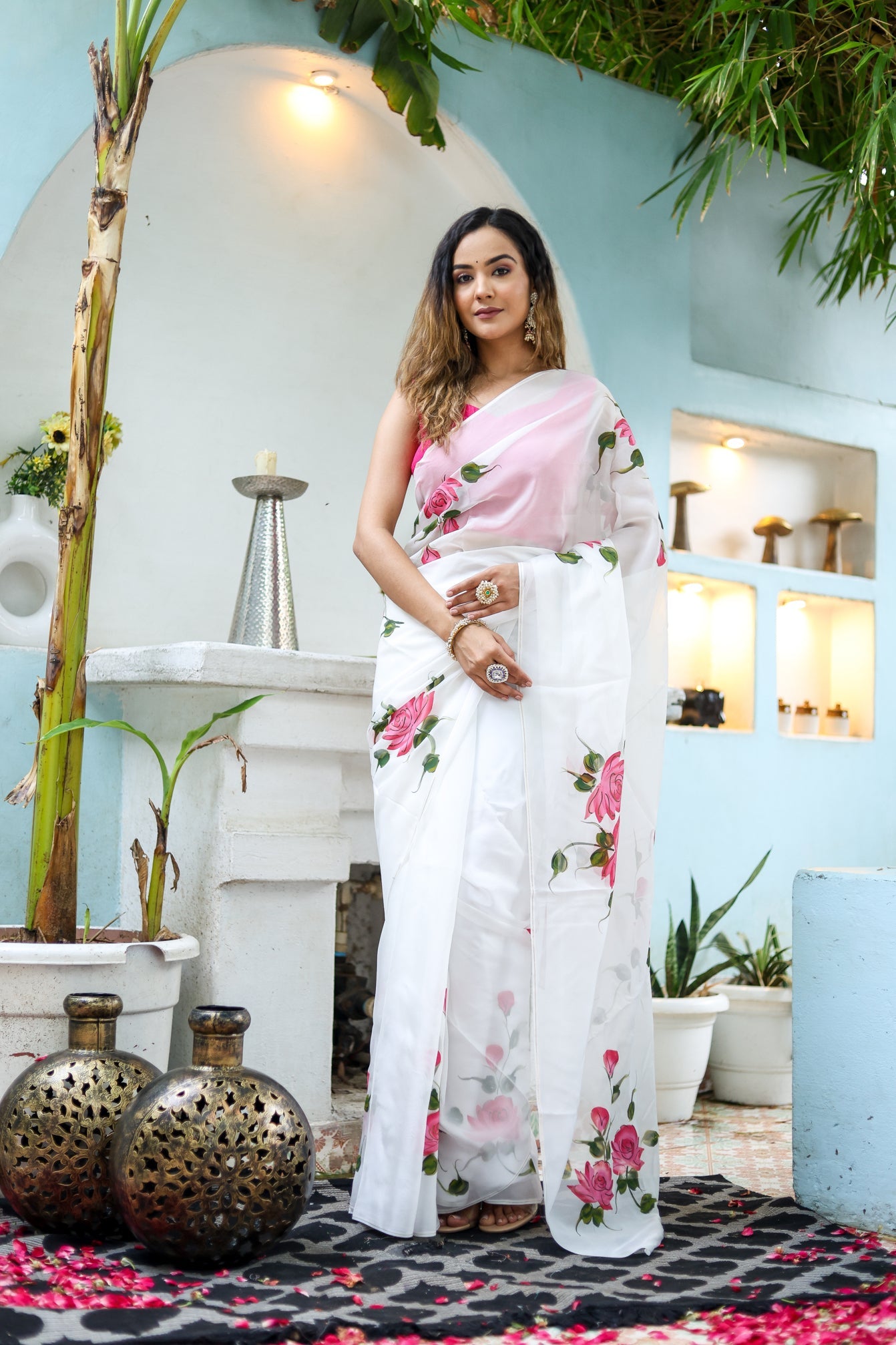 Elegant white floral saree for women with pink flowers, styled in a serene outdoor setting