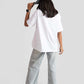 Back view of woman wearing white oversized anime t-shirt for women styled with wide-leg jeans and denim cap