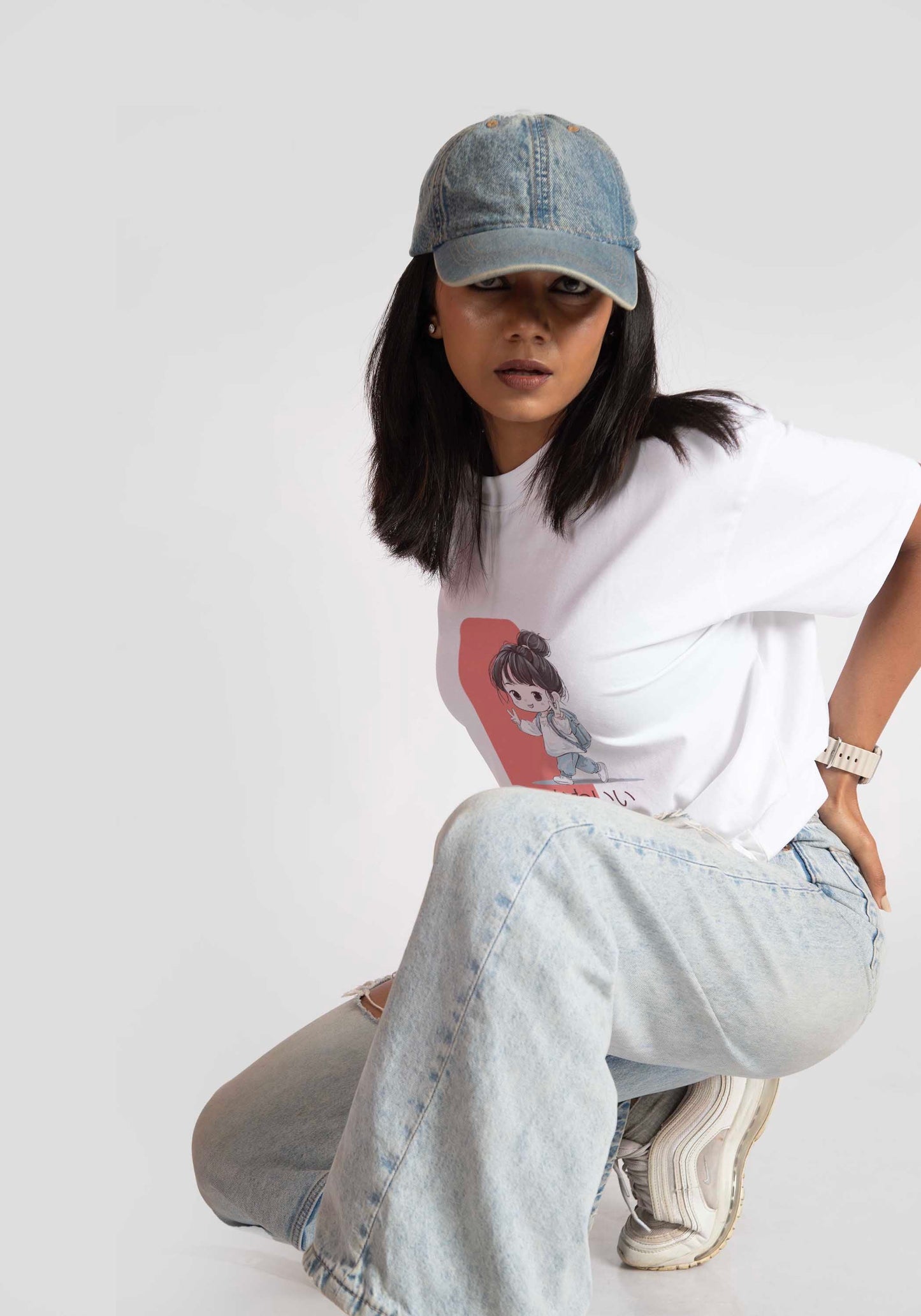 Woman wearing white oversized anime t-shirt for women paired with light blue jeans and denim cap