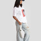 White oversized anime t-shirt for women styled with light washed ripped jeans and blue denim cap