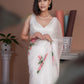 Elegant woman wearing a white saree with pink floral print, showcasing a sophisticated style with a lightweight design