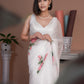 Elegant model wearing a white saree with pink floral print, showcasing a classic design and delicate details