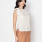 white sleeveless blouse with bow detail on shoulder worn with brown pants