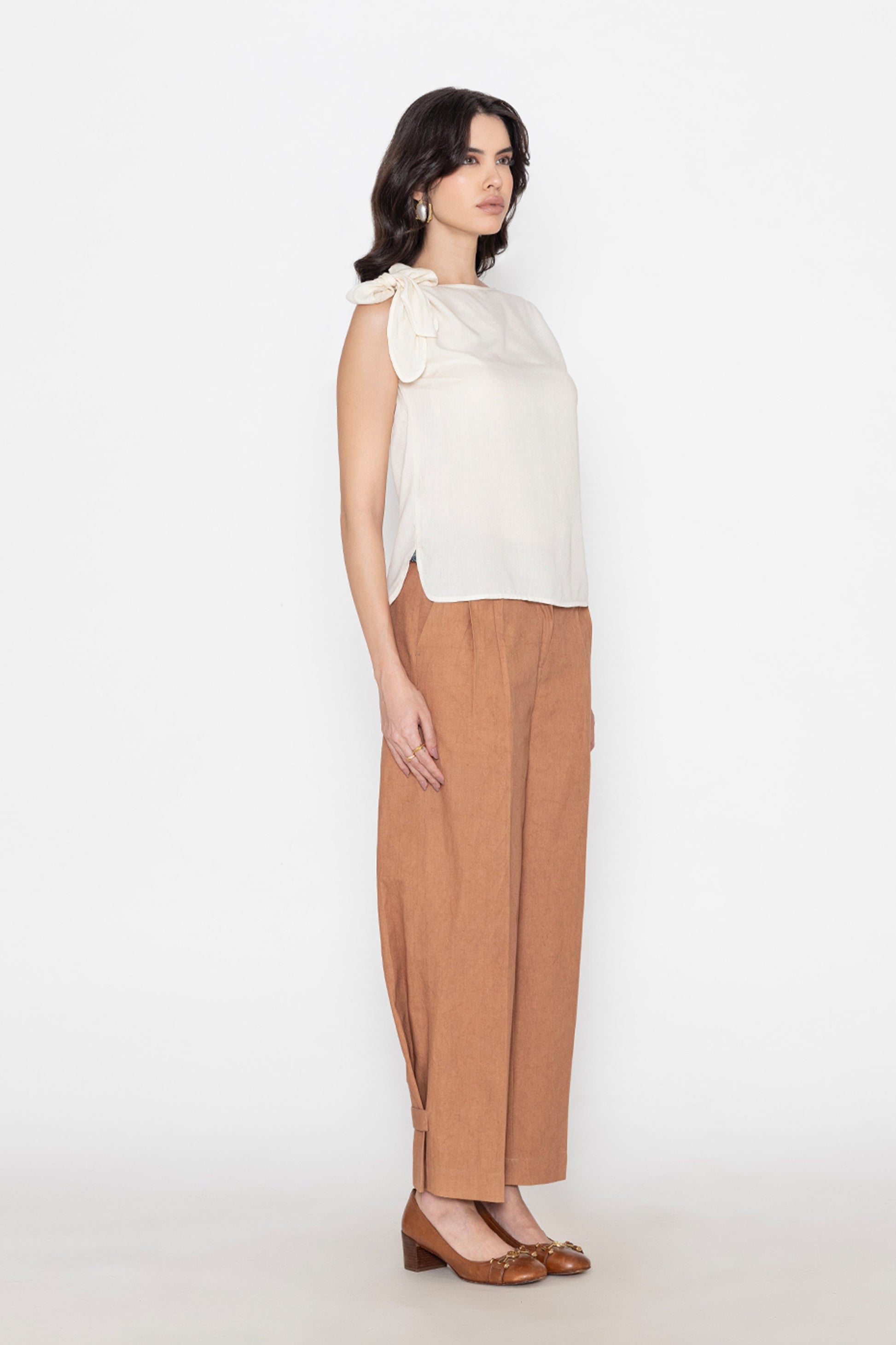 white sleeveless blouse with shoulder tie detail paired with brown wide-leg pants