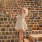 Model wearing a white summer dress for women standing on outdoor stone steps