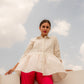 Model wearing a white tunic top casual wear paired with vibrant pink pants against a cloudy sky