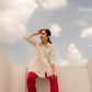 Model wearing a white tunic top casual wear paired with pink pants against a cloudy sky