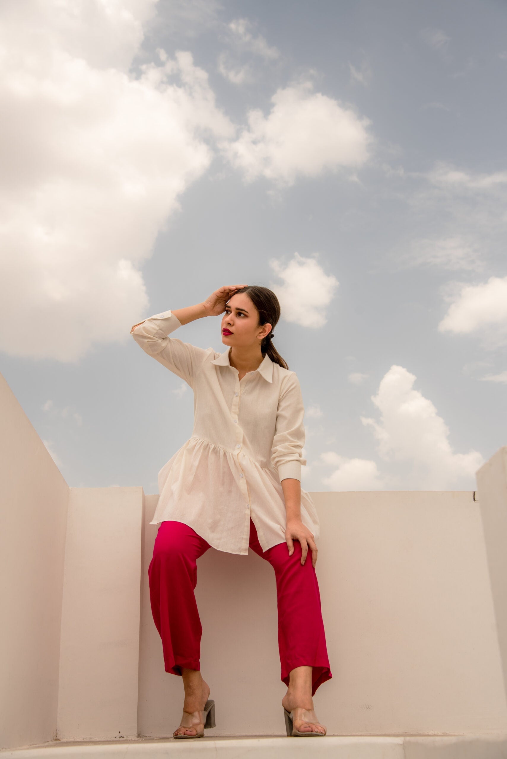 Model wearing a white tunic top casual wear paired with pink pants against a cloudy sky