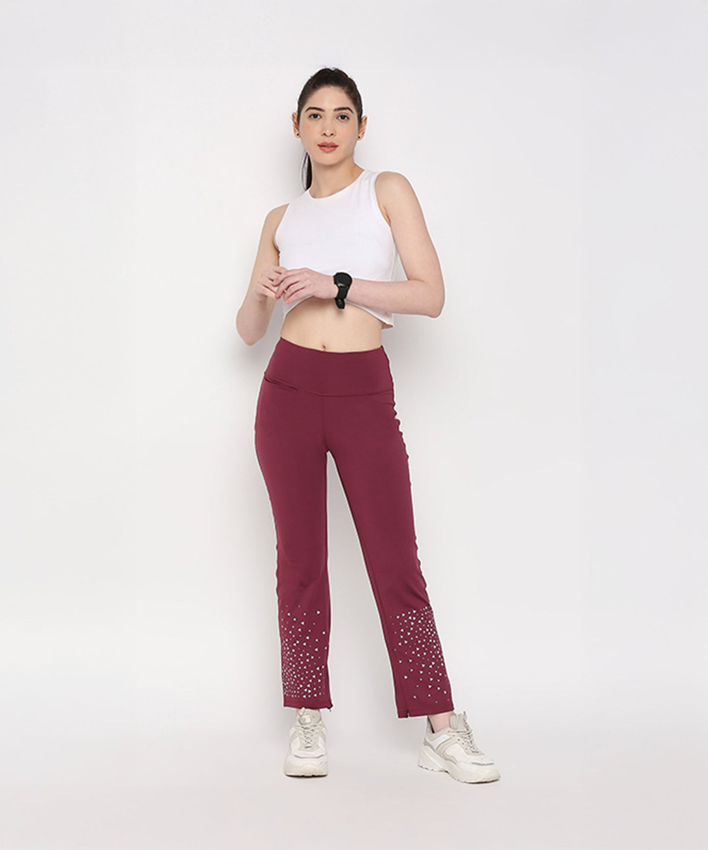 Model wearing a white twisted crop top paired with burgundy leggings for a stylish active look