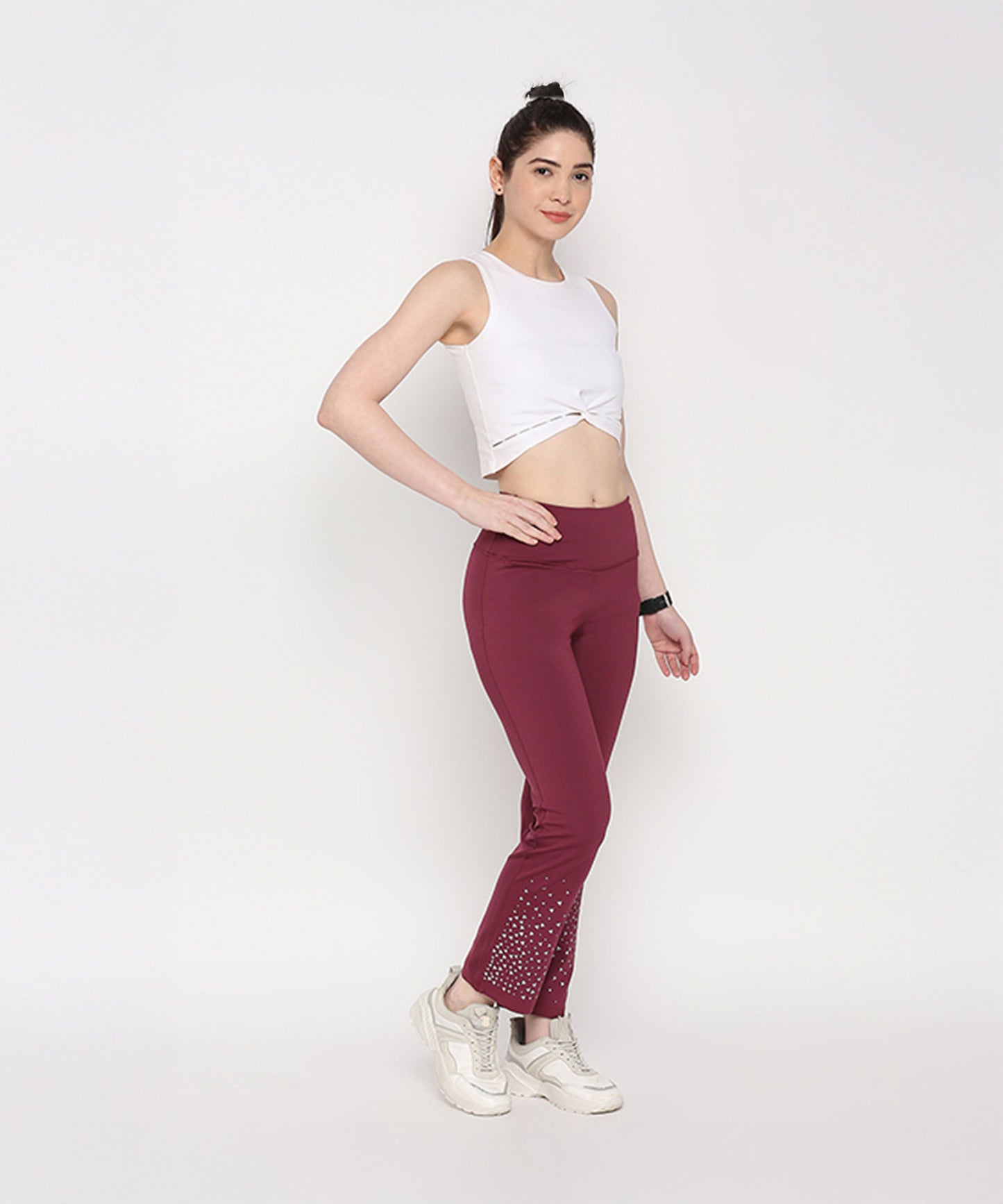 Model wearing a white twisted crop top paired with maroon workout pants for an active look
