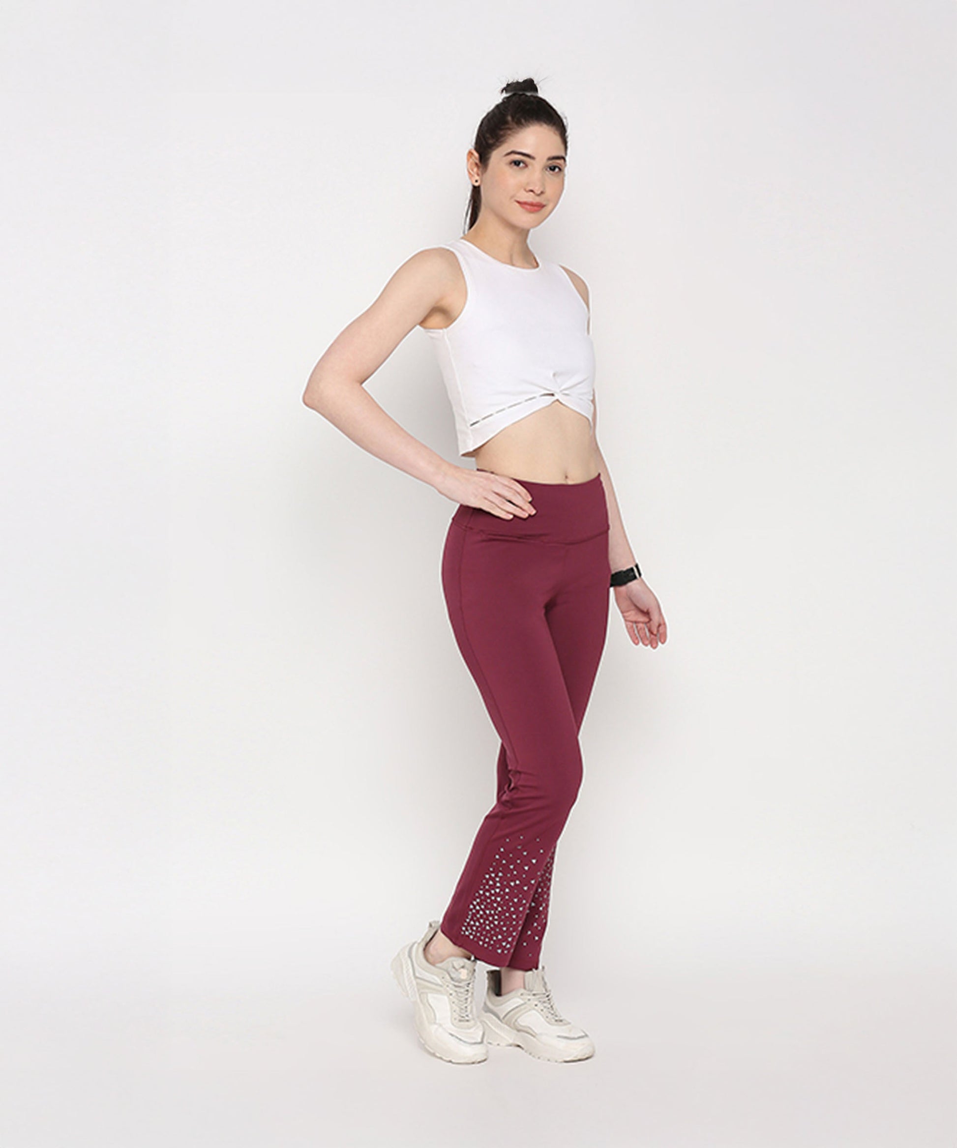 Model wearing a white twisted crop top paired with maroon workout pants for an active look