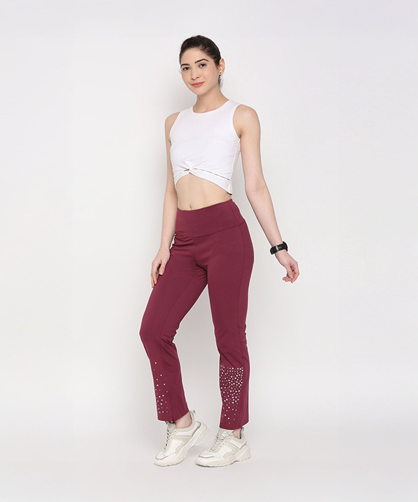 Model wearing a white twisted crop top with maroon gym pants featuring embellishments