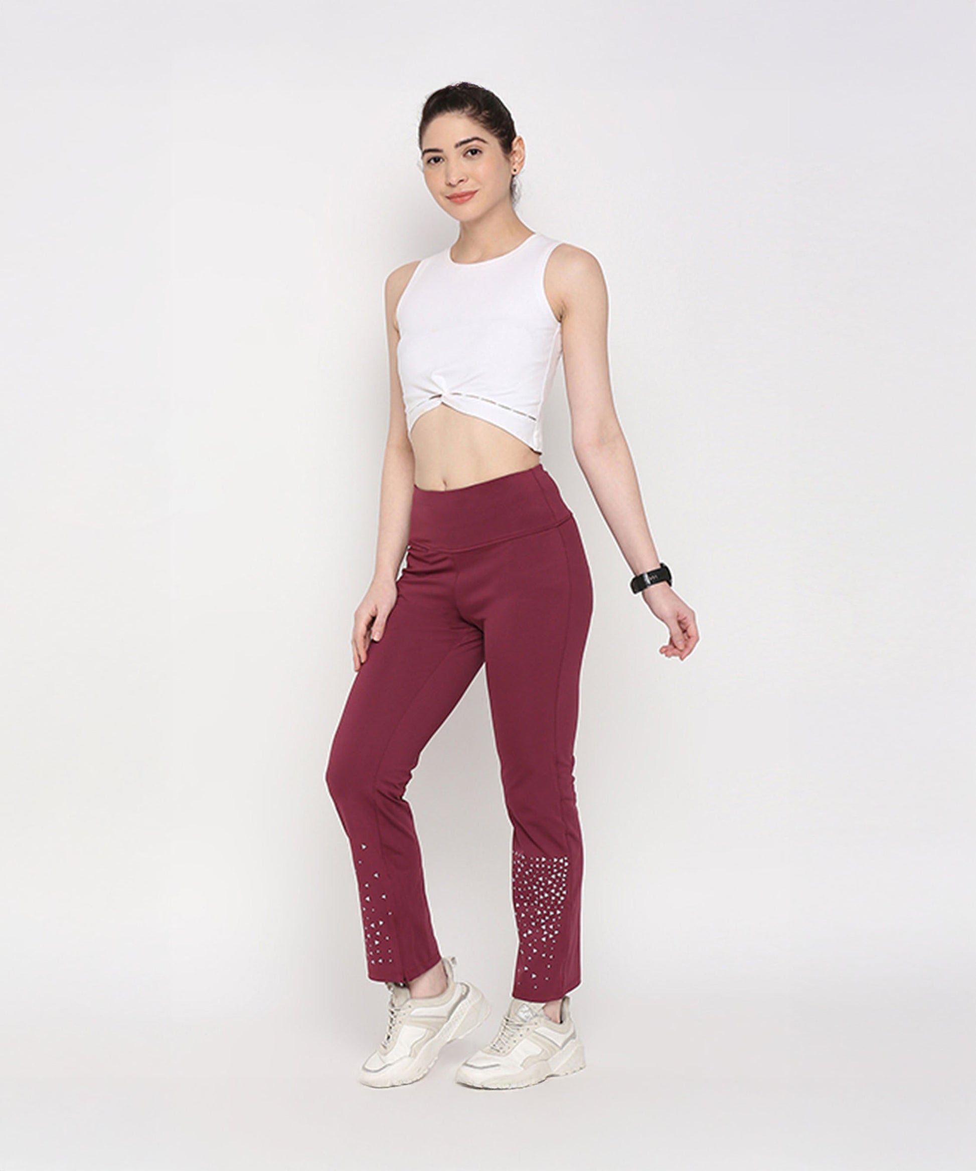 Model wearing a white twisted crop top with maroon gym pants featuring embellishments