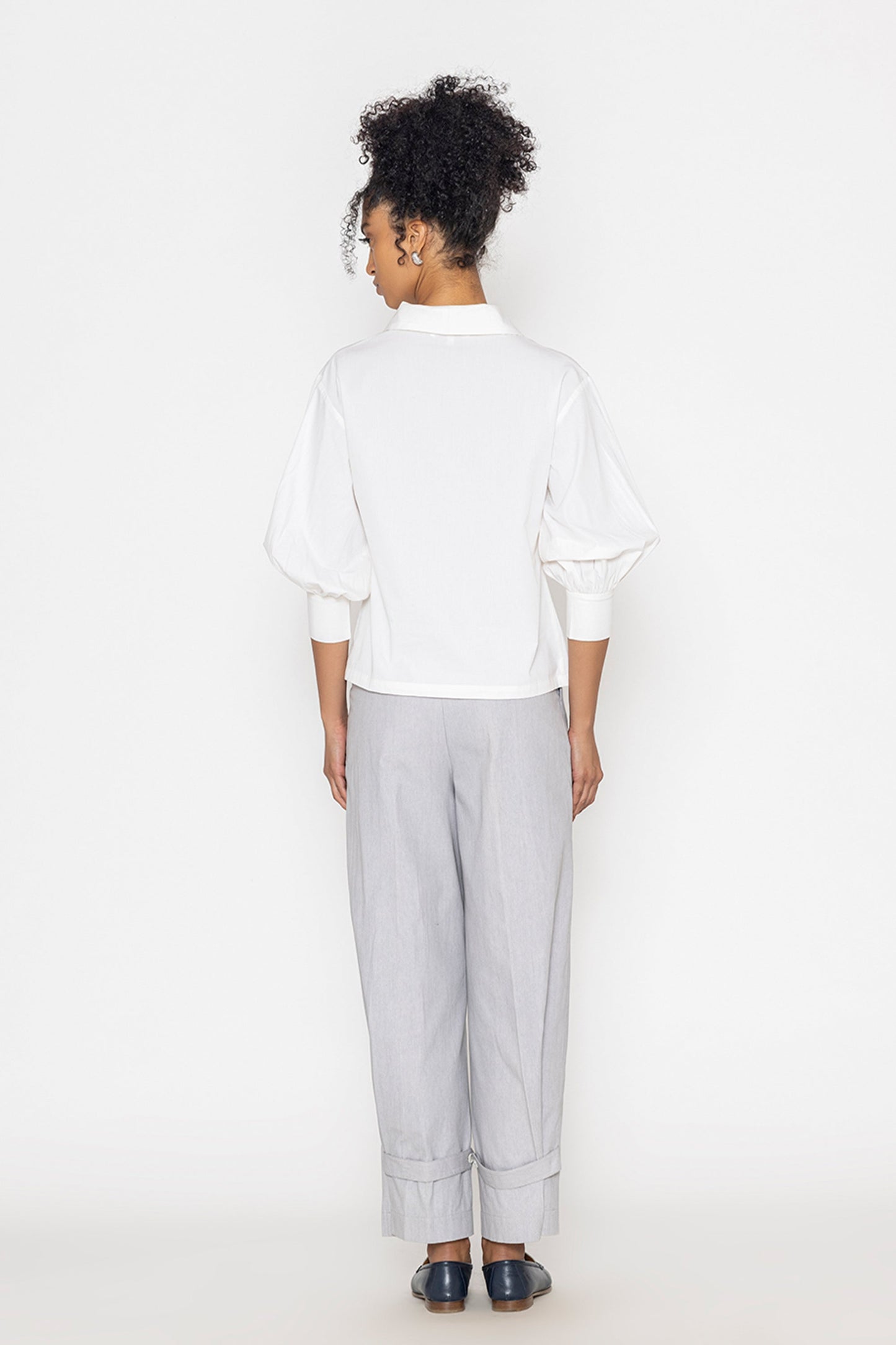 Back view of woman wearing Stylera white v-neck blouse for women with puff sleeves and fitted cuffs