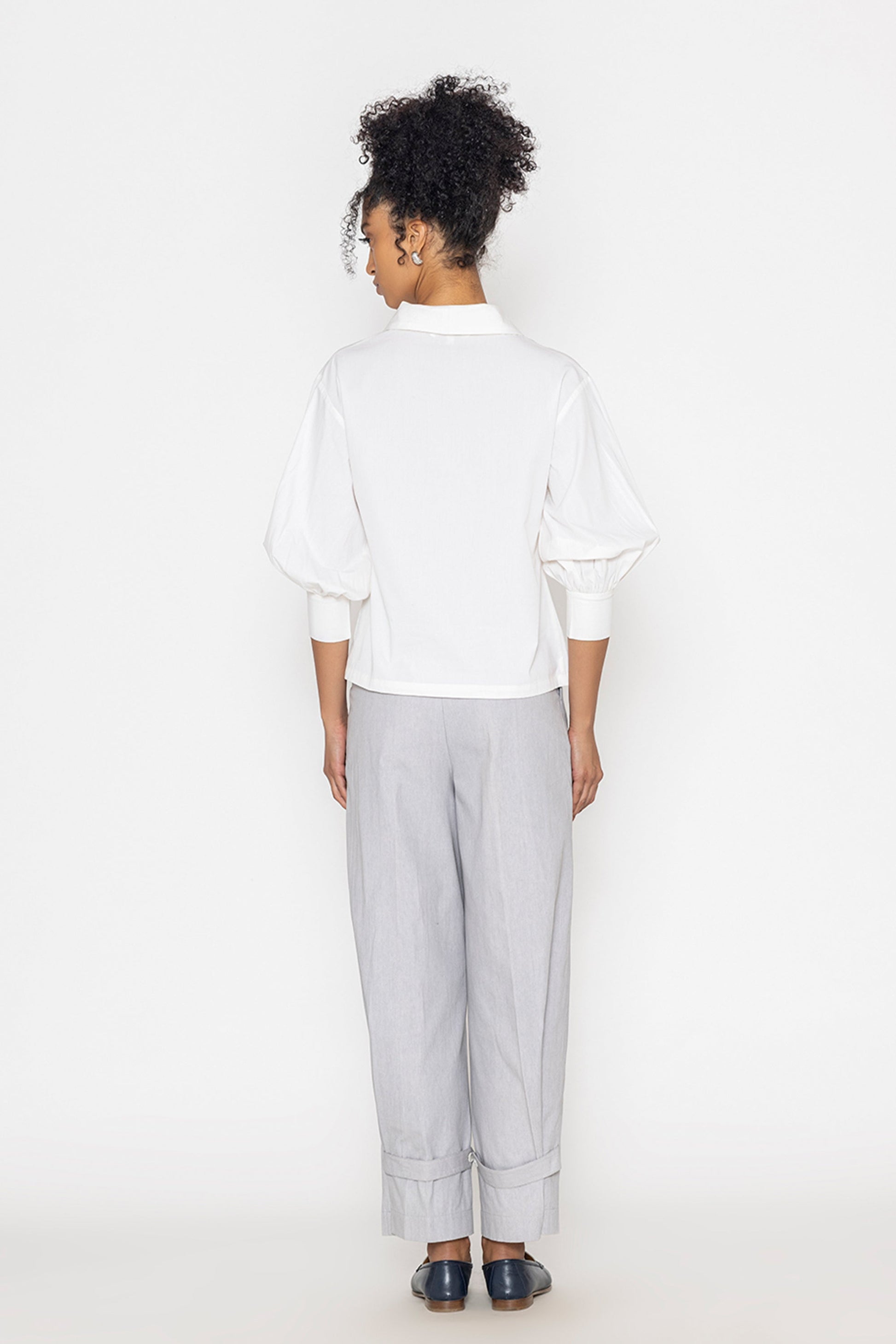 Back view of woman wearing Stylera white v-neck blouse for women with puff sleeves and fitted cuffs