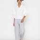 Stylera white v-neck blouse for women with three-quarter puff sleeves worn with gray pants