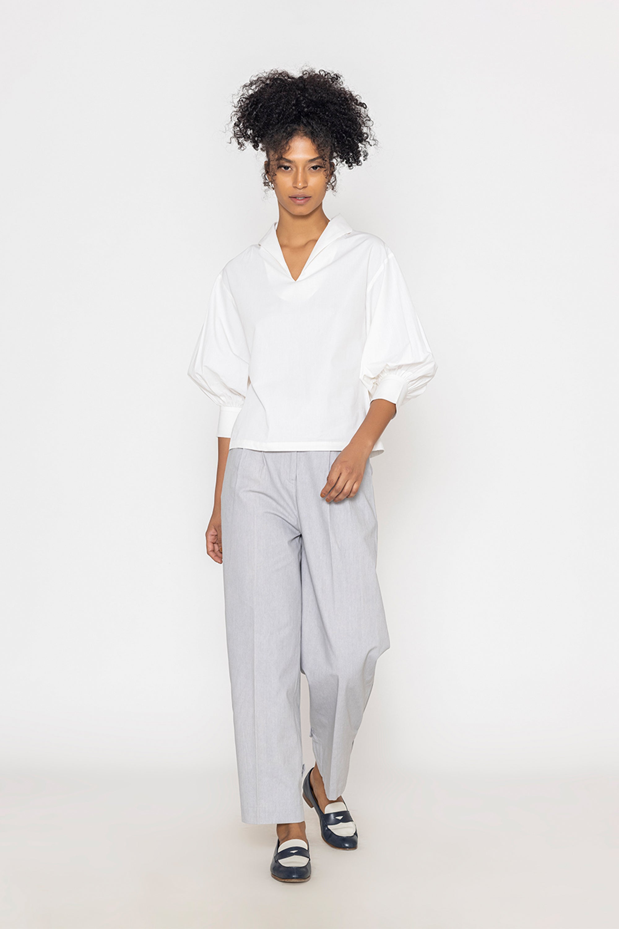 Stylera white v-neck blouse for women with three-quarter puff sleeves worn with gray pants