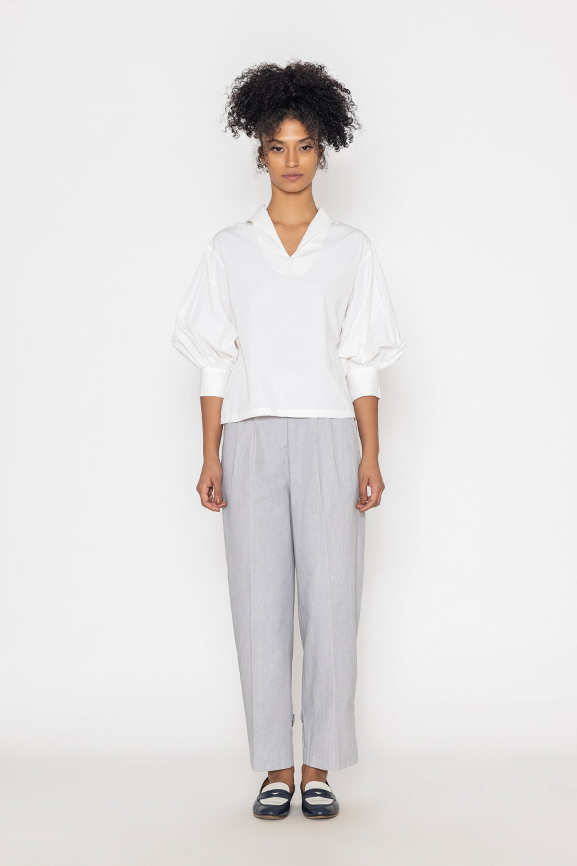 Stylera white v-neck blouse for women with puffed sleeves paired with light gray pants