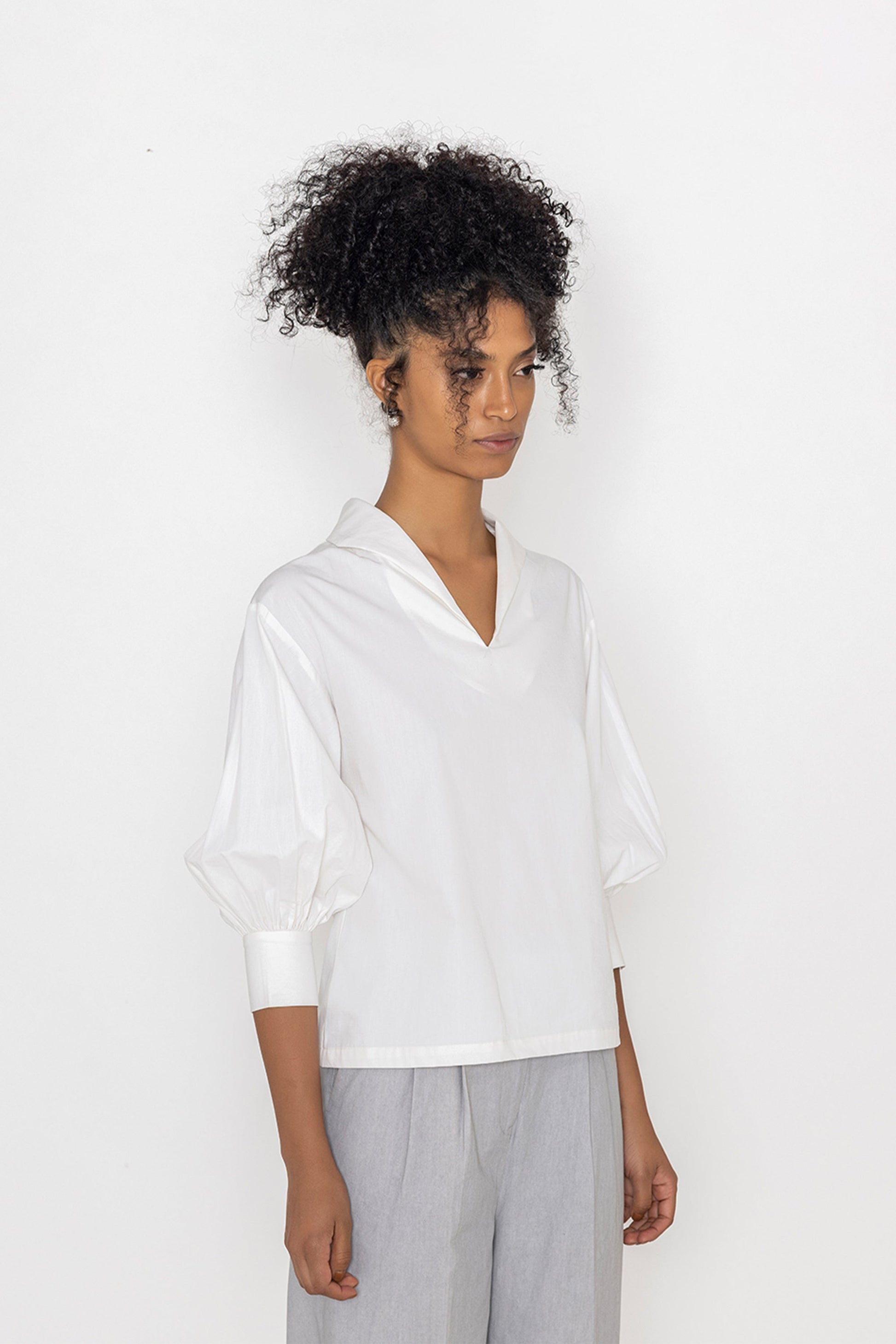 Stylera white v-neck blouse for women with puff sleeves styled with gray pants