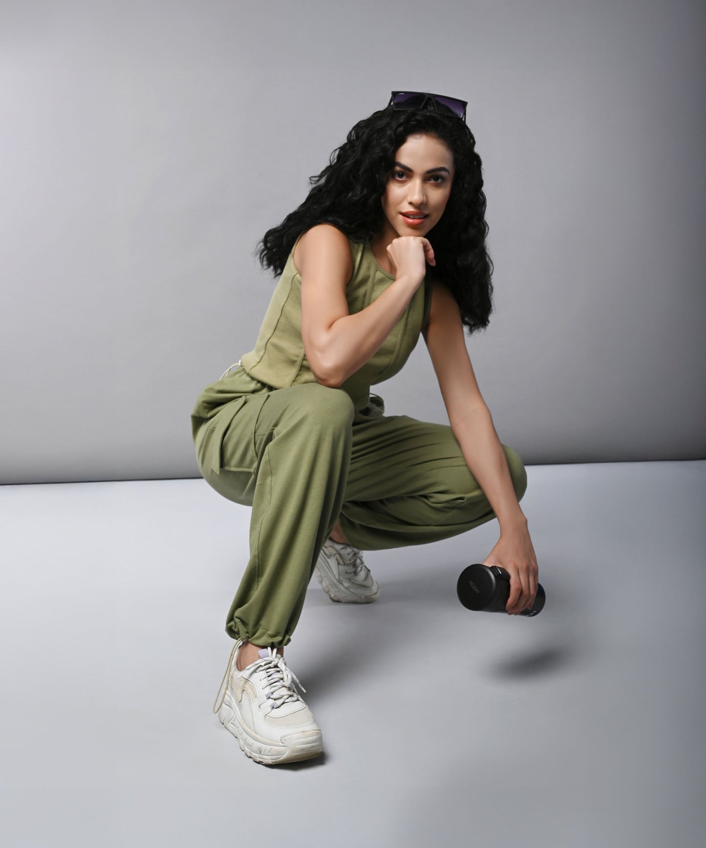 Model wearing women's cargo parachute pants with crop top in olive green, styled for casual fitness looks