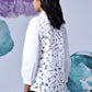 Rear view of model wearing Stylera women's casual chic white shirt with floral lace cutout back