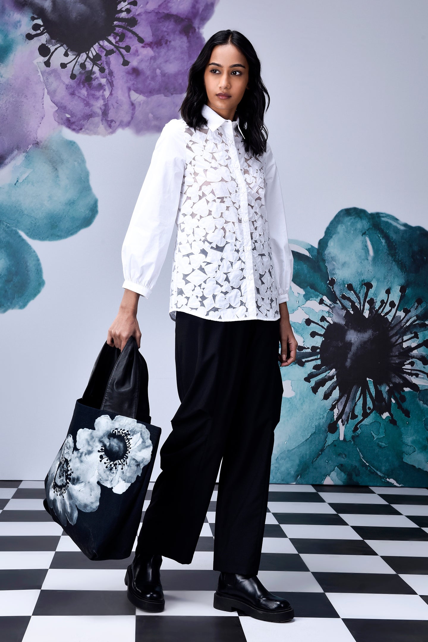 Stylera model wearing women's casual chic white shirt with lace front balloon sleeves black pants and floral tote