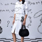 Stylera model wearing white knee length women’s casual shirt dress with print black bag